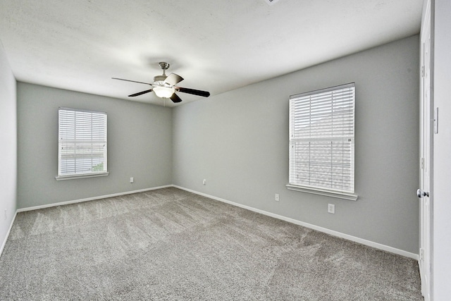 carpeted empty room featuring ceiling fan and a wealth of natural light