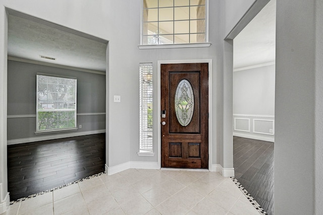 entrance foyer featuring light hardwood / wood-style floors, a healthy amount of sunlight, and ornamental molding