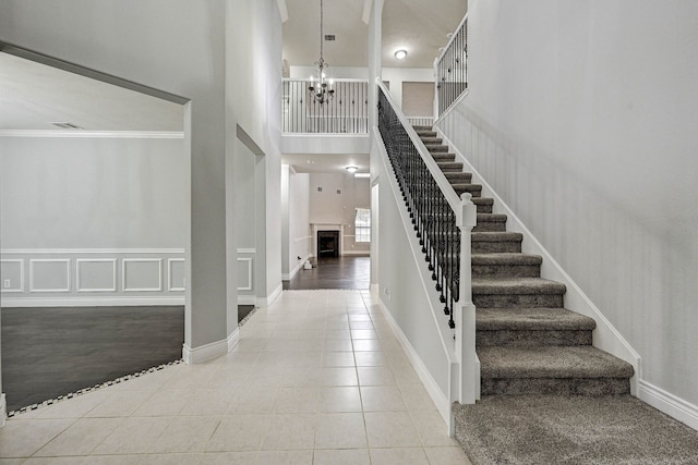 tiled entrance foyer featuring a towering ceiling, ornamental molding, and a notable chandelier