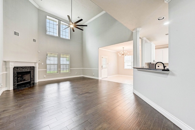 unfurnished living room with dark hardwood / wood-style floors, a towering ceiling, ornamental molding, and a wealth of natural light