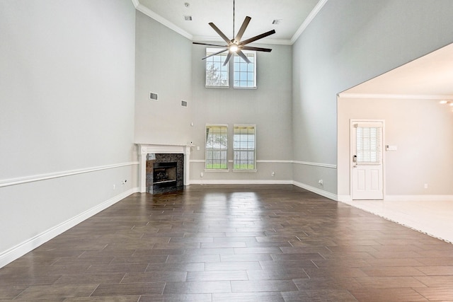 unfurnished living room with a high ceiling, a wealth of natural light, ornamental molding, and ceiling fan