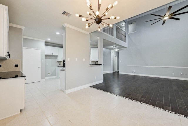 unfurnished living room with ceiling fan with notable chandelier, light wood-type flooring, and crown molding