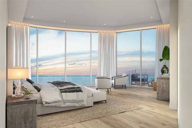 bedroom featuring a water view, light wood-type flooring, and recessed lighting