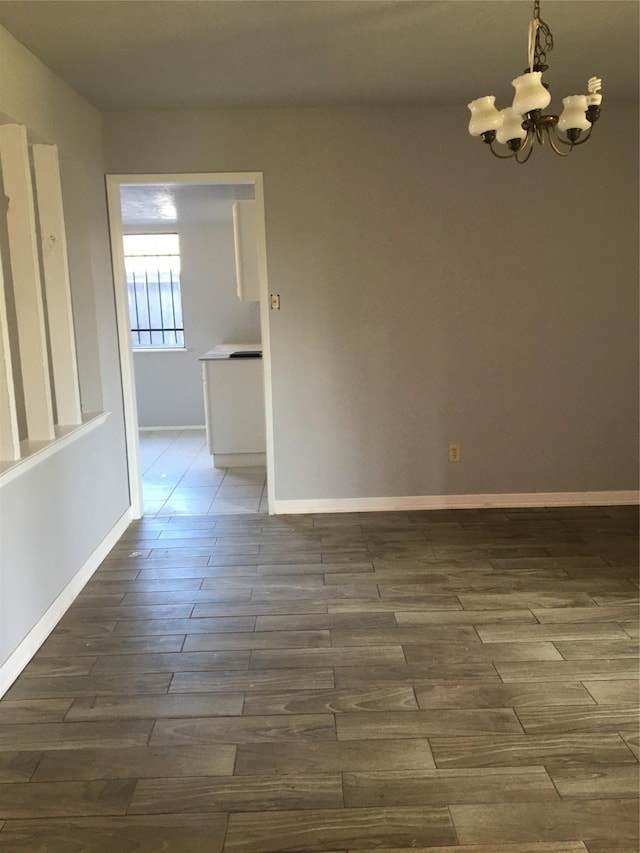 spare room with dark hardwood / wood-style flooring and a notable chandelier