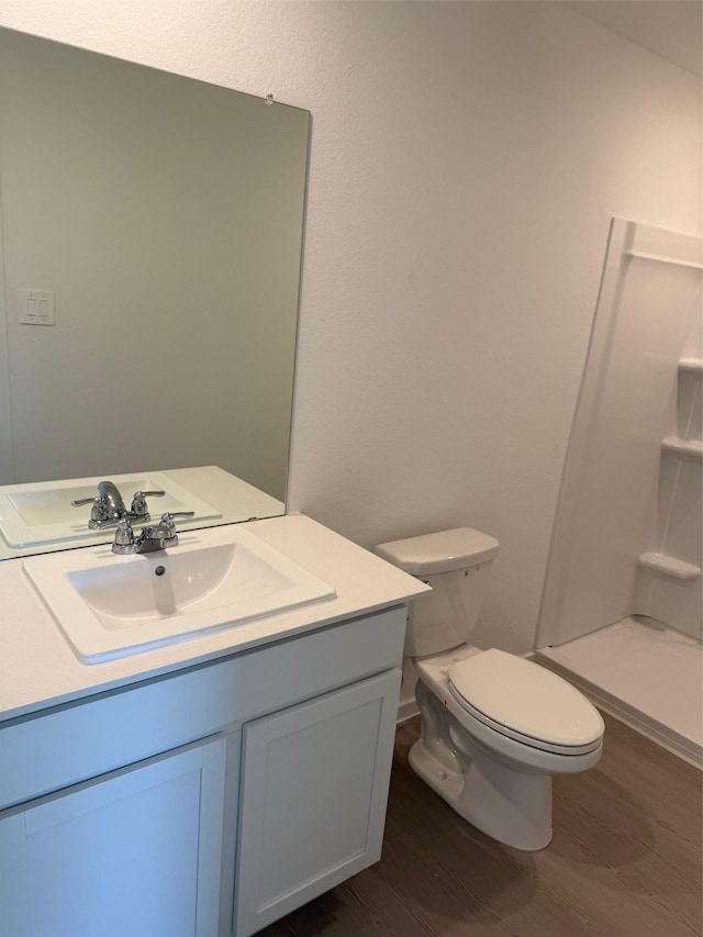 bathroom with a shower, hardwood / wood-style floors, vanity, and toilet