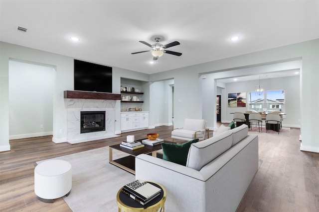 living room with a fireplace, wood-type flooring, and ceiling fan