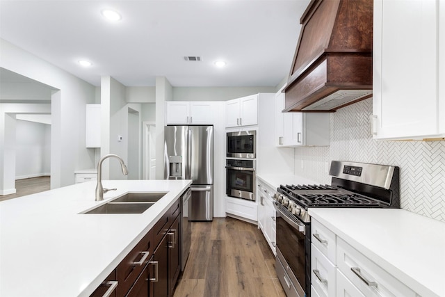 kitchen featuring white cabinetry, sink, stainless steel appliances, wood-type flooring, and custom range hood