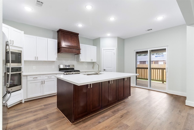 303 Kalmer St, Pasadena, TX 77502 - kitchen featuring appliances with stainless steel finishes, premium range hood, light countertops, decorative backsplash, and an island with sink