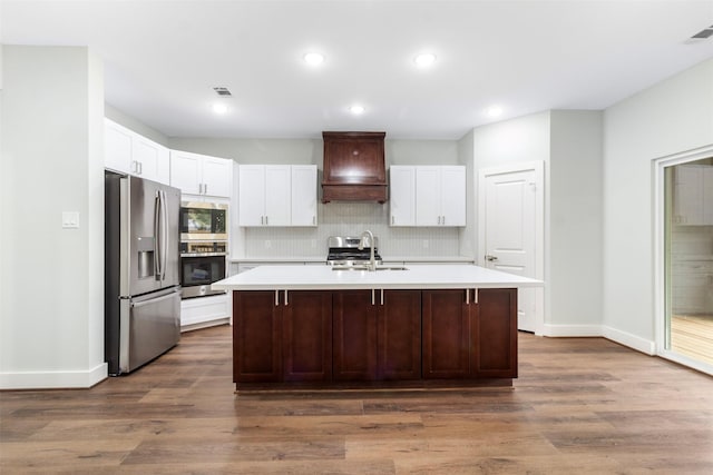 kitchen featuring a center island with sink, sink, dark hardwood / wood-style floors, custom range hood, and stainless steel appliances