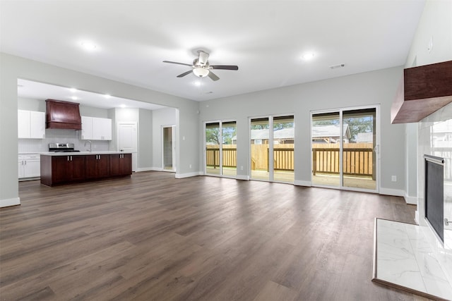 unfurnished living room featuring dark hardwood / wood-style floors, ceiling fan, and sink