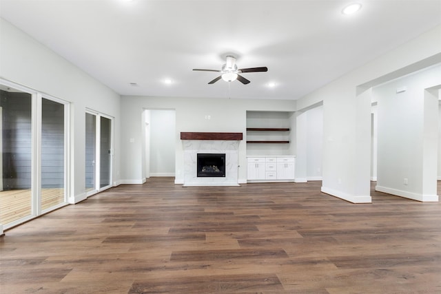 unfurnished living room featuring a high end fireplace, dark hardwood / wood-style flooring, and ceiling fan