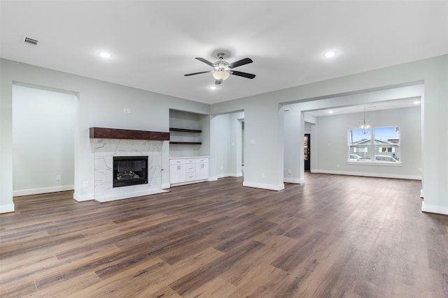 unfurnished living room with dark hardwood / wood-style floors, ceiling fan, and a tiled fireplace