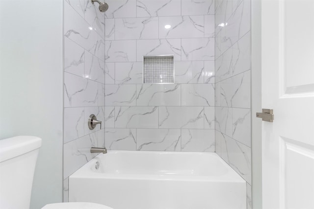 bathroom with tiled shower / bath combo and toilet