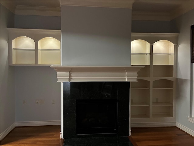 room details with a tiled fireplace, ornamental molding, baseboards, and wood finished floors