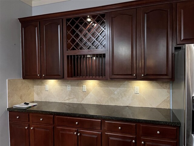 kitchen featuring tasteful backsplash, stainless steel refrigerator, and dark stone counters