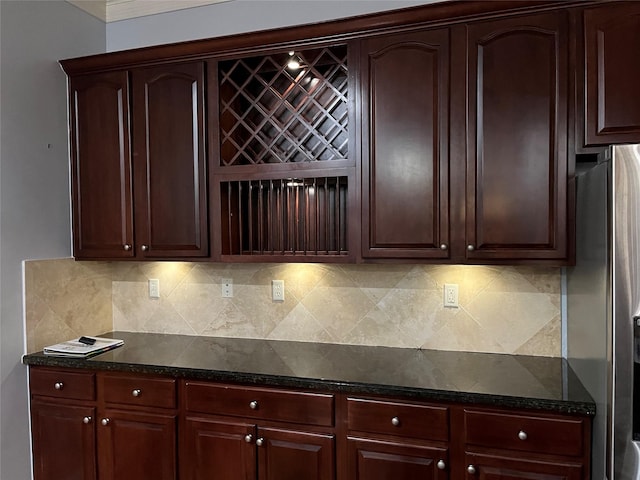 kitchen with decorative backsplash, stainless steel fridge, and dark stone counters