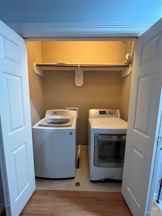 clothes washing area featuring washing machine and dryer and light tile patterned flooring