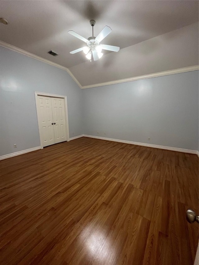 unfurnished bedroom with lofted ceiling, ceiling fan, crown molding, dark wood-type flooring, and a closet