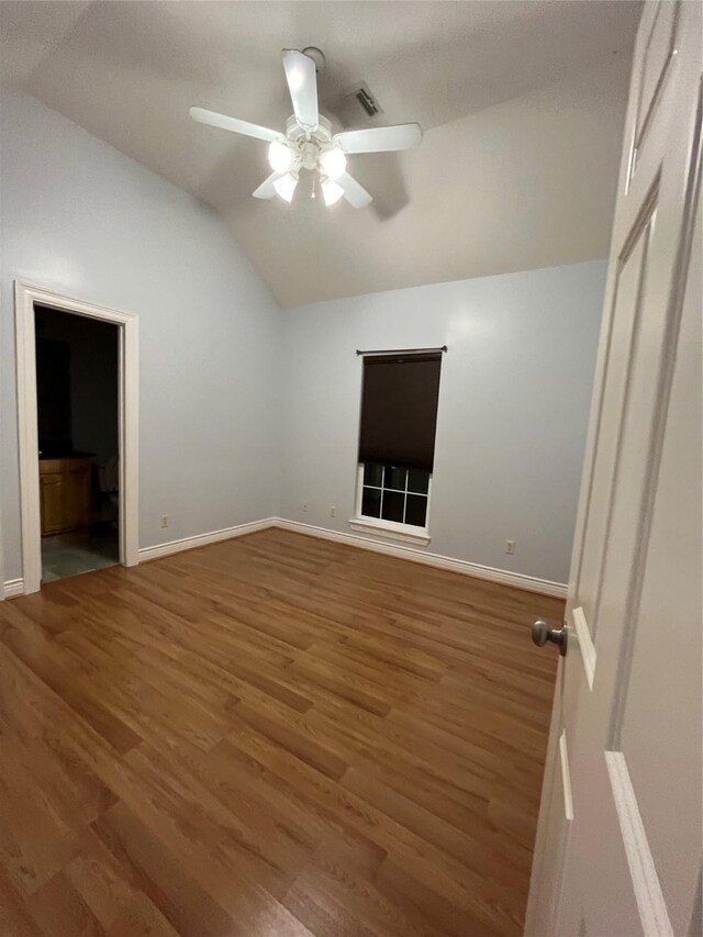 unfurnished bedroom featuring hardwood / wood-style flooring, ceiling fan, vaulted ceiling, and ensuite bath