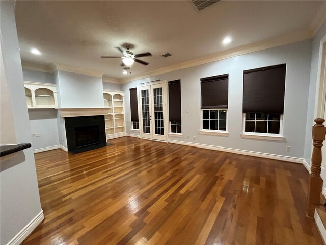 unfurnished living room featuring french doors, crown molding, wood-type flooring, built in features, and ceiling fan