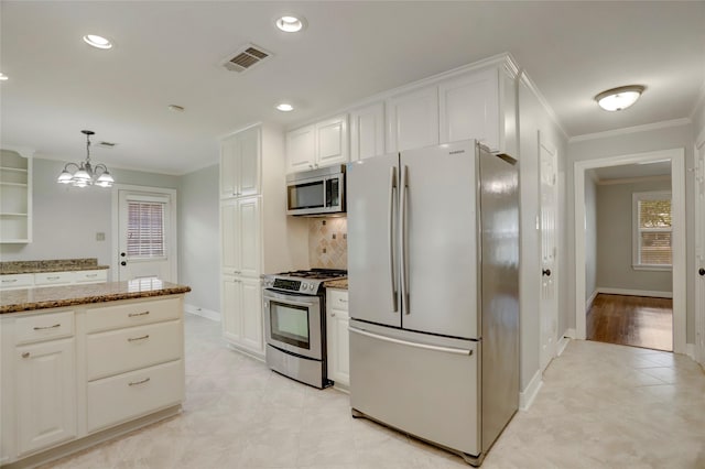 kitchen featuring pendant lighting, white cabinetry, stainless steel appliances, and a chandelier