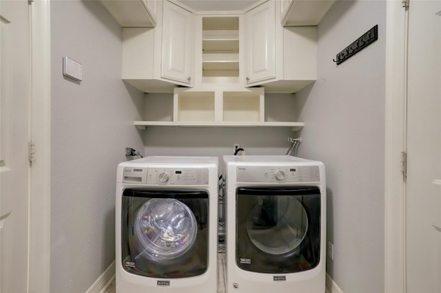 clothes washing area featuring cabinets and washing machine and clothes dryer