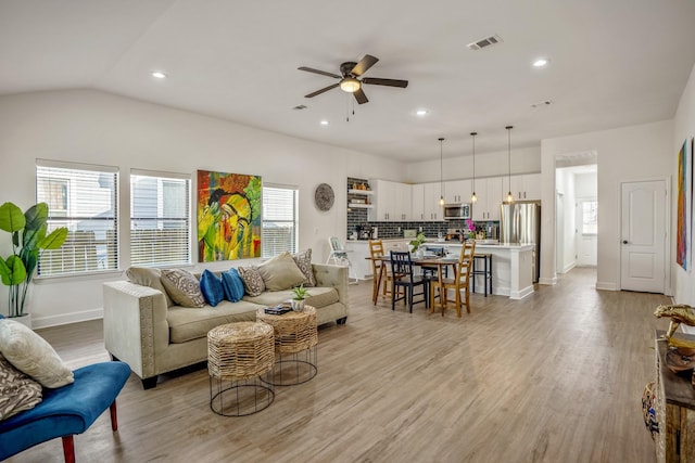 living room with ceiling fan, light hardwood / wood-style floors, lofted ceiling, and a wealth of natural light