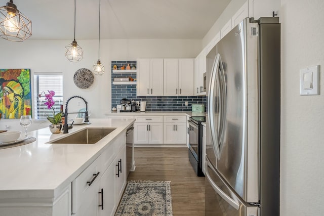 kitchen featuring dark wood-type flooring, white cabinets, sink, decorative light fixtures, and stainless steel appliances