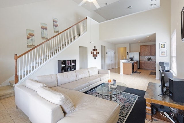 living room with ceiling fan, light tile patterned floors, and a high ceiling