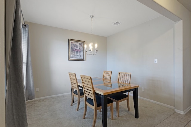 dining space with light colored carpet and an inviting chandelier