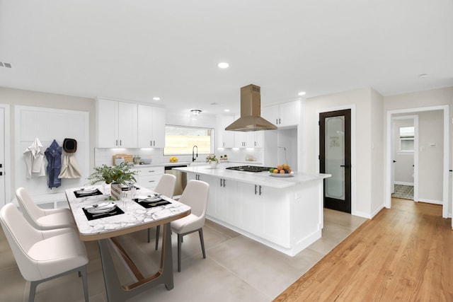 kitchen featuring island range hood, sink, white cabinets, light hardwood / wood-style floors, and a kitchen island