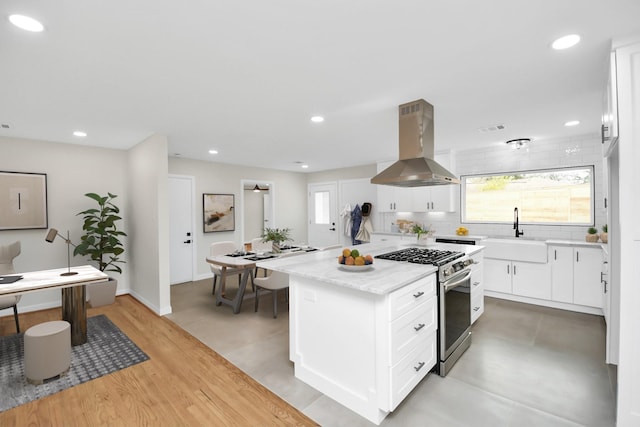 kitchen featuring white cabinetry, sink, high end stainless steel range, a kitchen island, and exhaust hood