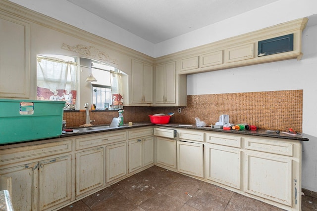 kitchen featuring cream cabinetry, sink, dark tile patterned floors, and backsplash