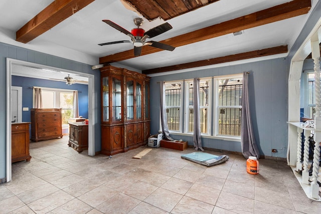 interior space with ceiling fan and beamed ceiling