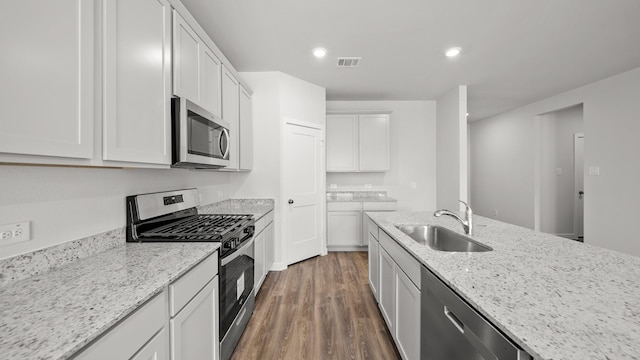 kitchen featuring sink, white cabinets, dark wood-type flooring, light stone counters, and stainless steel appliances