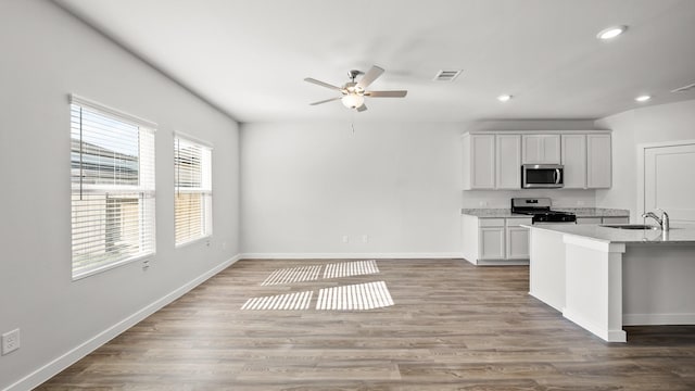 kitchen with white cabinetry, stainless steel appliances, ceiling fan, sink, and hardwood / wood-style flooring