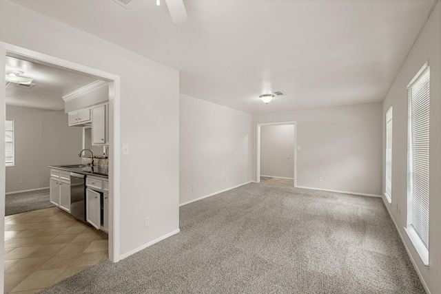 carpeted spare room featuring ceiling fan, crown molding, and sink