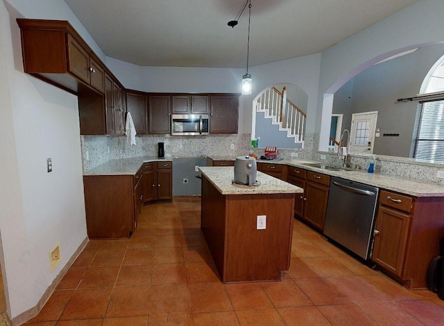 kitchen with sink, a center island, hanging light fixtures, tasteful backsplash, and appliances with stainless steel finishes