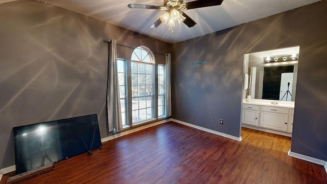 unfurnished bedroom with ceiling fan, ensuite bathroom, and dark wood-type flooring