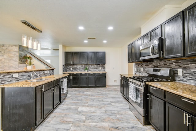 kitchen with sink, tasteful backsplash, light stone counters, pendant lighting, and appliances with stainless steel finishes