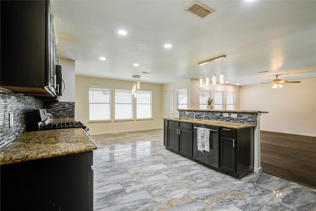 kitchen with decorative backsplash, stainless steel appliances, light stone counters, and hanging light fixtures