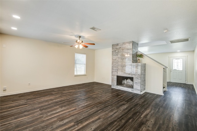 unfurnished living room with ceiling fan, dark hardwood / wood-style flooring, and a tiled fireplace