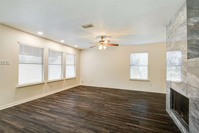 unfurnished living room featuring ceiling fan, a fireplace, and dark wood-type flooring