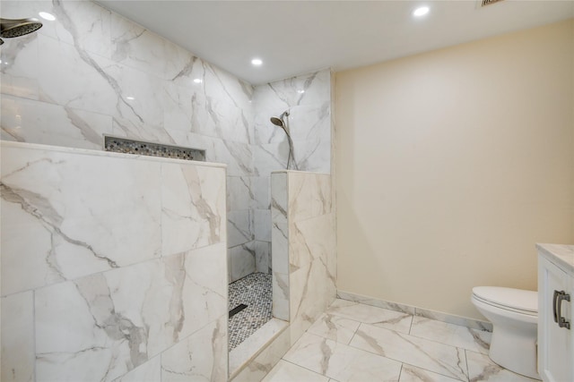 bathroom with tiled shower, vanity, and toilet