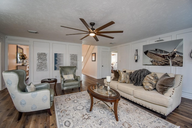 living room featuring ceiling fan, dark hardwood / wood-style flooring, and a textured ceiling