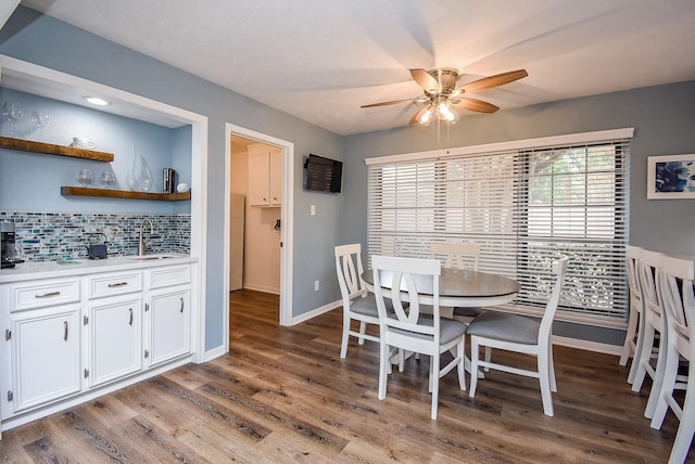 dining area with hardwood / wood-style flooring, ceiling fan, and sink