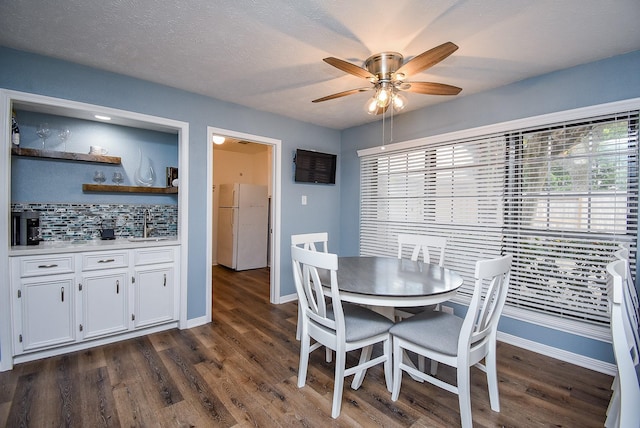 dining room with ceiling fan, dark hardwood / wood-style floors, sink, and a textured ceiling