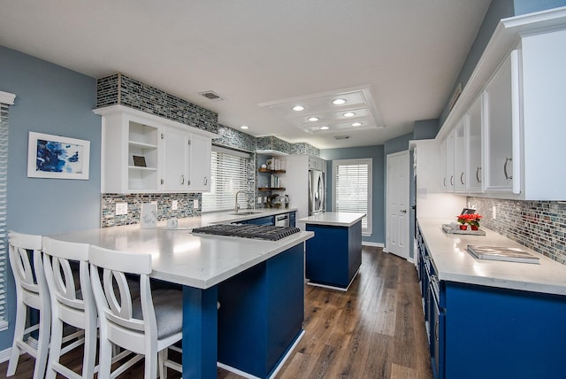 kitchen featuring a breakfast bar, a center island, white cabinets, and sink