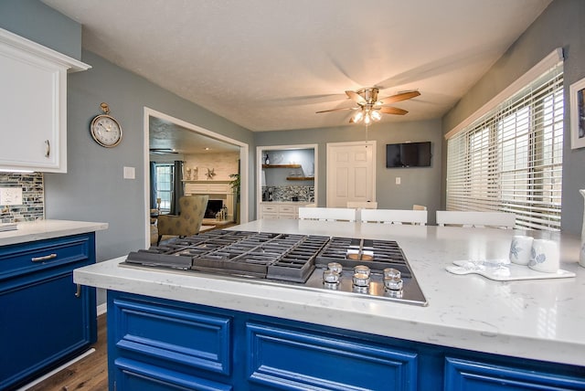 kitchen with blue cabinetry, ceiling fan, white cabinetry, dark hardwood / wood-style floors, and stainless steel gas stovetop