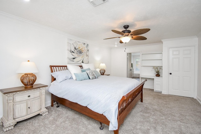 carpeted bedroom with ceiling fan, ornamental molding, and a textured ceiling